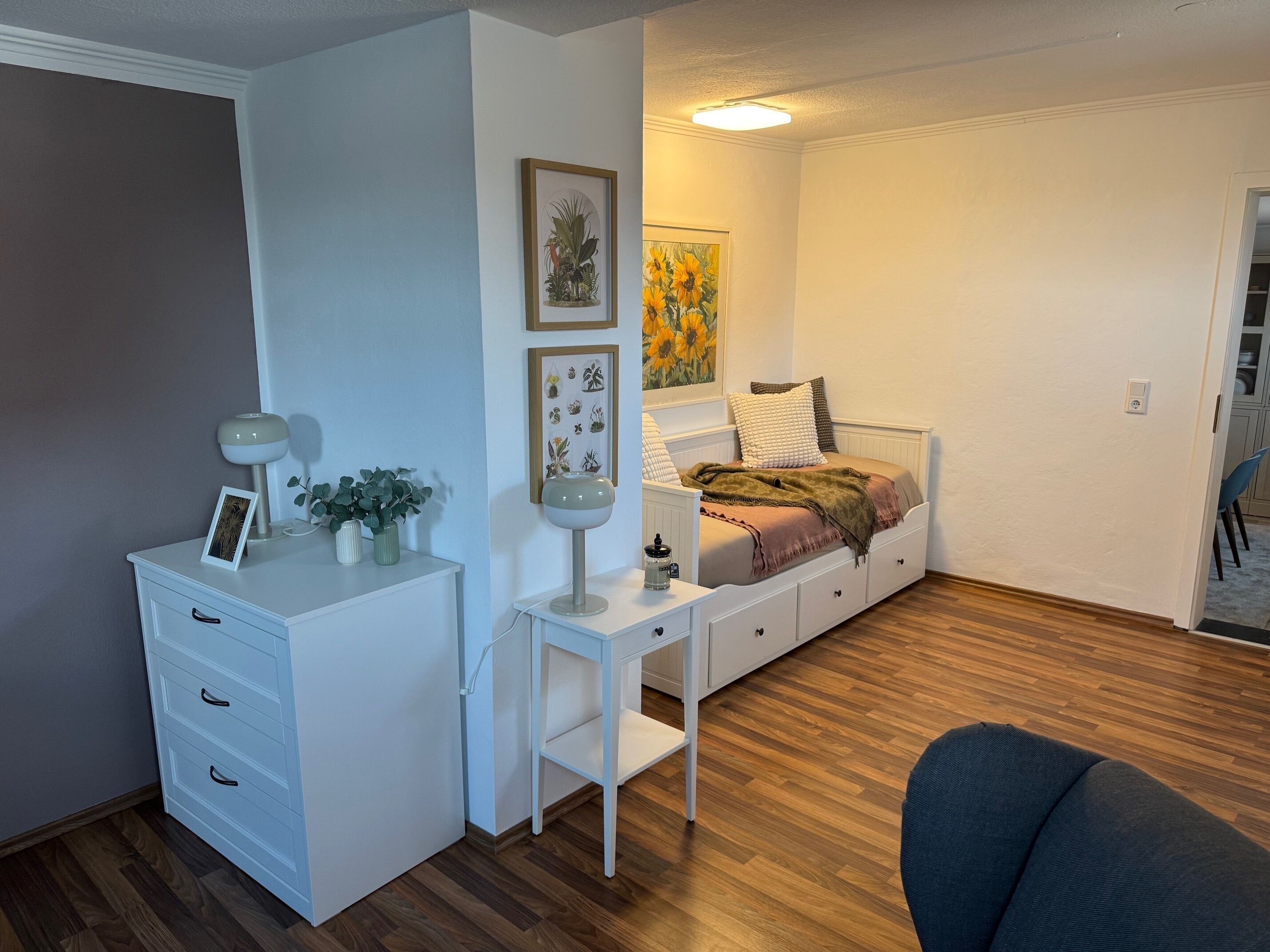 Une chambre à coucher comprenant un lit, une table de chevet, une commode et un bureau avec une lampe.