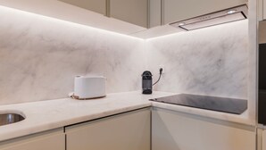 Una cocina moderna con encimera de mármol, un tostador, una cafetera y un lavavajillas.