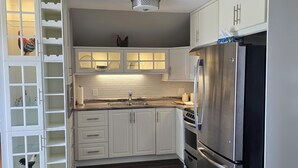 Una cocina moderna con armarios blancos, un refrigerador de acero inoxidable y un horno empotrado.