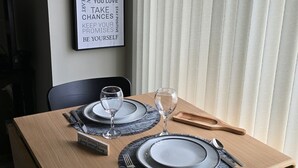 Una mesa de comedor con platos, cubiertos y vasos, con una cita motivacional en la pared de fondo.