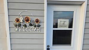 Una casa con un cartel que dice 'WELCOME', una puerta con ventana y un felpudo.