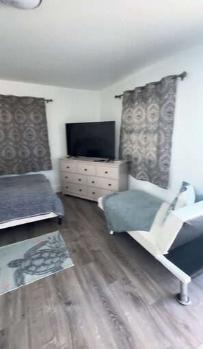Un dormitorio con cama, cómoda, televisor y silla.