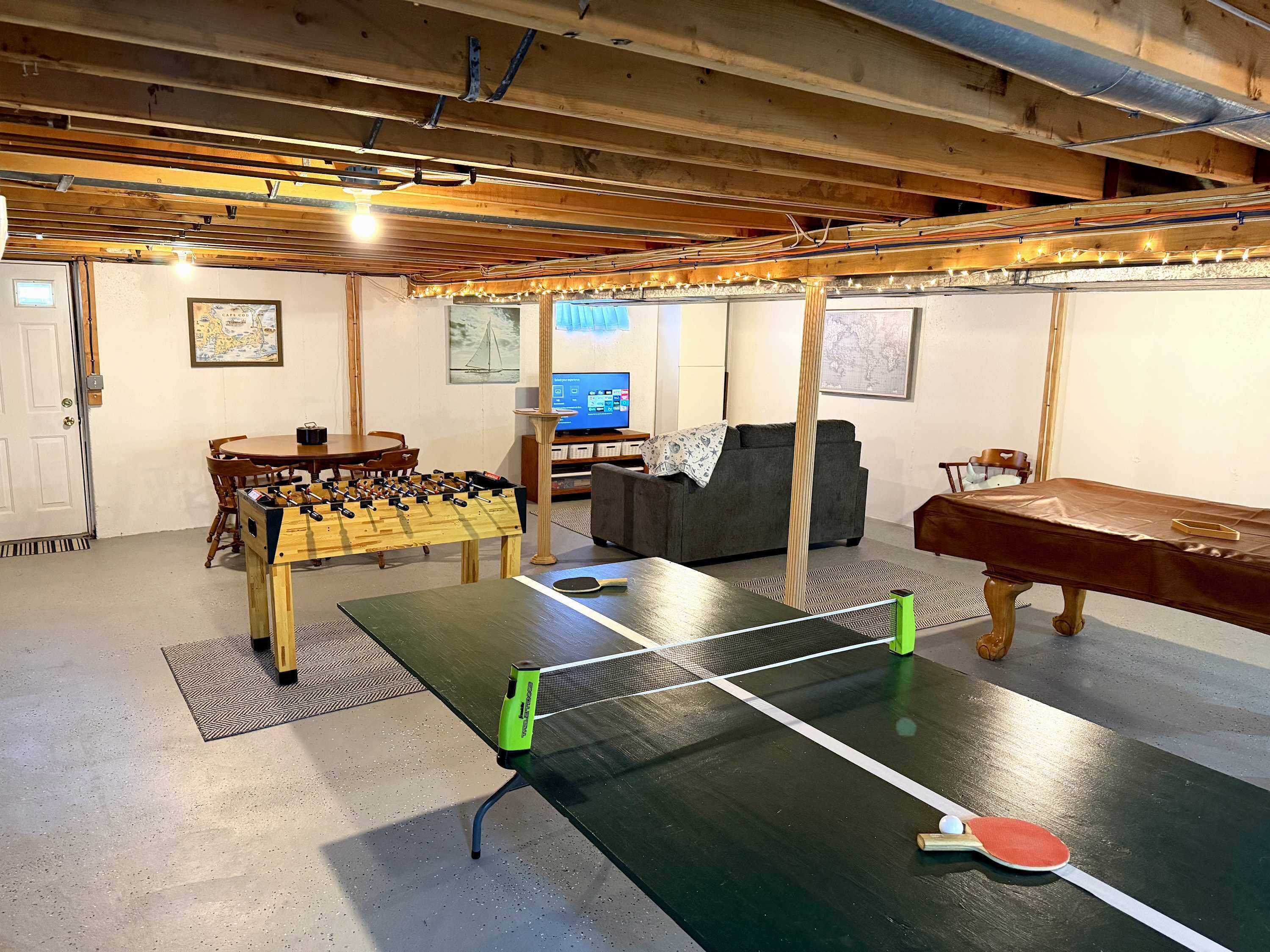 Een kamer met een tafeltennistafel, een tafelvoetbalspel en een bank.