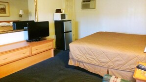 A hotel room with a bed, a television on a wooden dresser, a refrigerator, and a microwave. - Motel Edgewood (Edgewood)