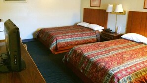 A hotel room with two beds, a desk with a computer, a lamp, and a framed picture on the wall.