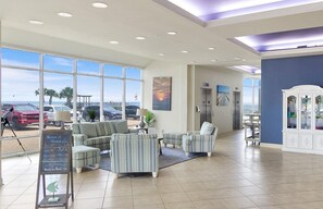 Eine geräumige Lobby mit großen Fenstern, bequemen Sitzgelegenheiten und Blick auf parkende Autos.