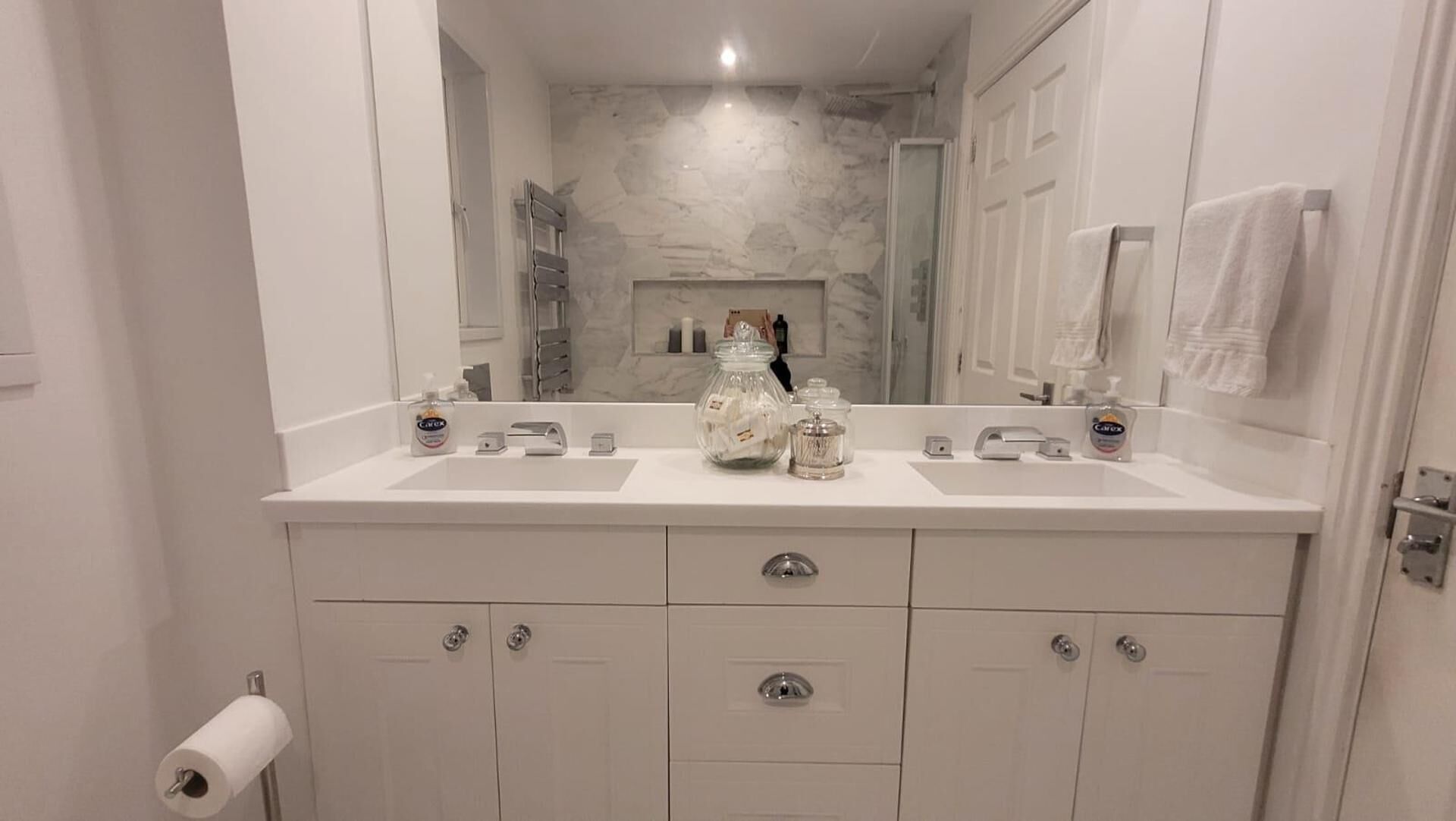 A bathroom with two sinks, a mirror, and storage cabinets.