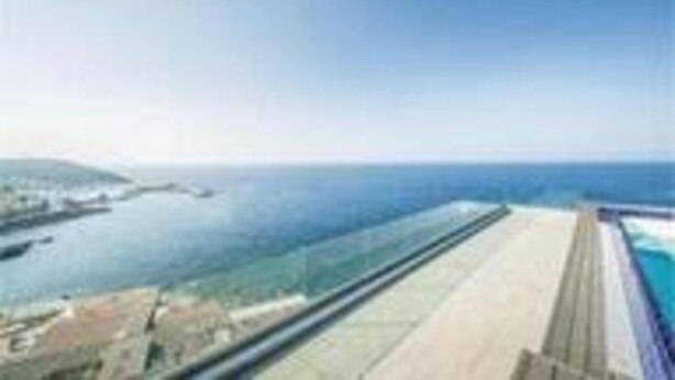 Una piscina larga y estrecha con vista al mar y una isla distante.