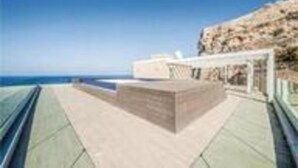 Un paseo marítimo con un banco de piedra y barandilla, con vistas al mar.