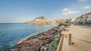 Un pueblo costero con un litoral rocoso, edificios a lo largo de la costa y un cielo despejado.
