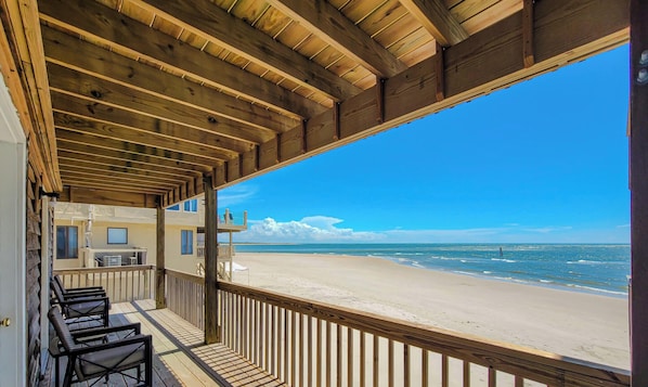 Une terrasse en bois offrant une vue sur la plage et l’océan.