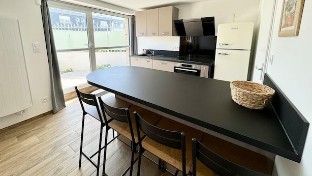 Una cocina moderna con una isla grande, sillas negras y una cesta tejida.