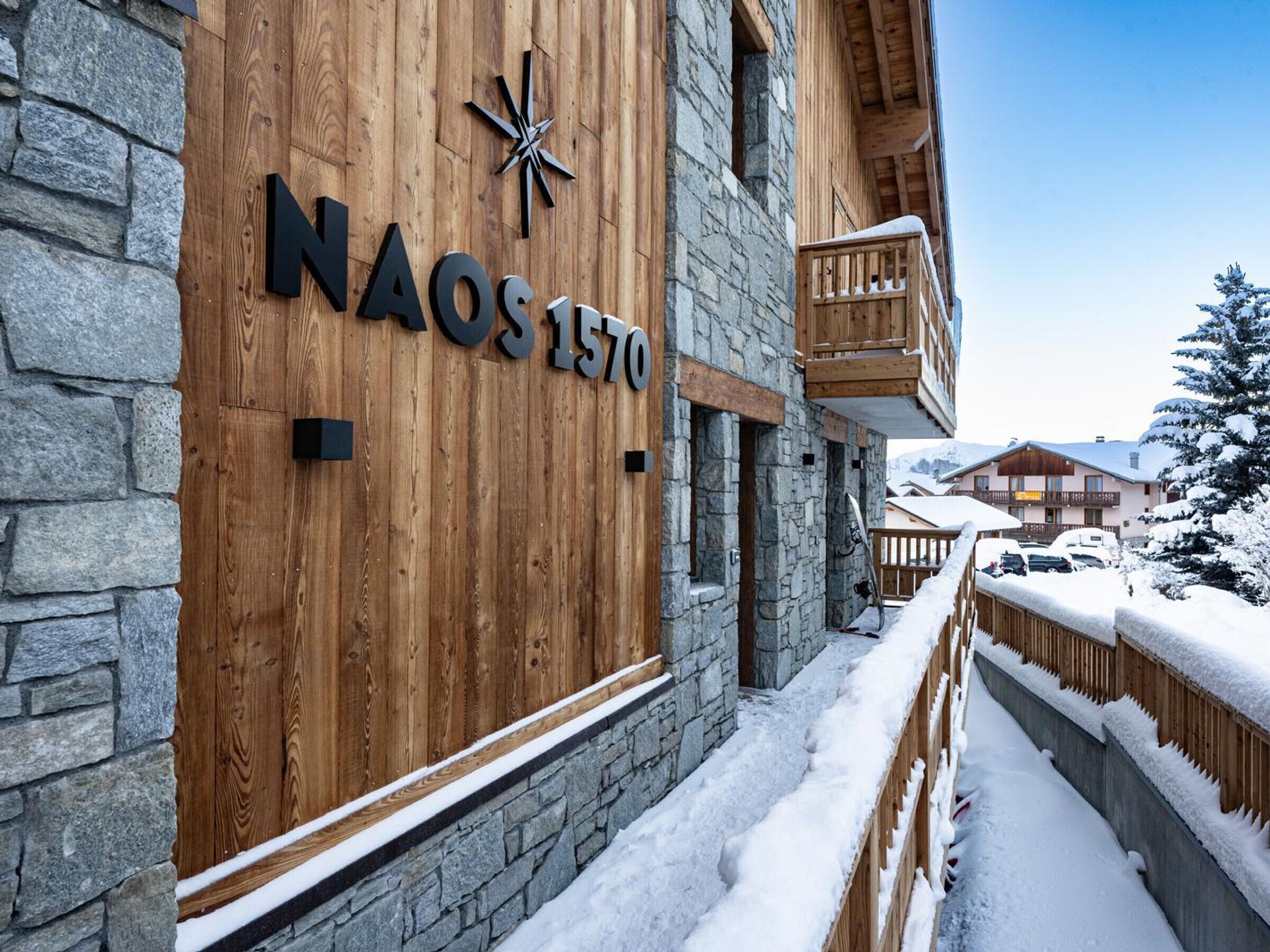 Un bâtiment en bois doté d’une façade en pierre et d’une enseigne indiquant « NAOS 1570 ».