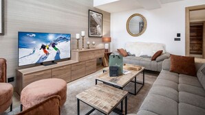 A modern living room with a flat-screen TV, wooden furniture, a grey sofa, and a mirror on the wall.