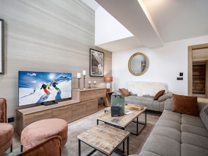 A modern living room with a flat-screen TV, wooden furniture, a grey sofa, and a mirror on the wall. - Ski-in Ski-out Apartment for 10 with Wifi (Saint-Martin-de-Belleville)
