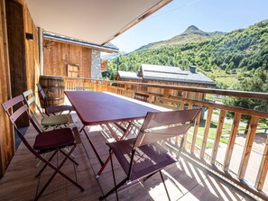A wooden balcony with a table and chairs, overlooking a mountainous landscape. - Ski-in Ski-out Apartment for 10 with Wifi (Saint-Martin-de-Belleville)