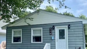 A single-story house with a front porch, two windows, a door, and a mailbox.