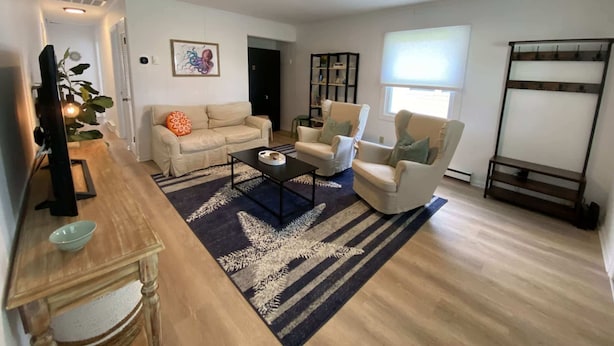 A living room with a sofa, armchairs, a coffee table, a TV, and a bookshelf.