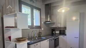 A compact kitchen with white cabinetry, a built-in dishwasher, and a coffee maker.