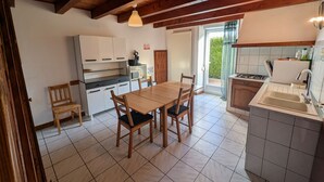 A kitchen with wooden cabinets, a dining table with chairs, a built-in oven, and a sink.