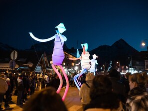 A nighttime outdoor event with illuminated figures and a crowd.
