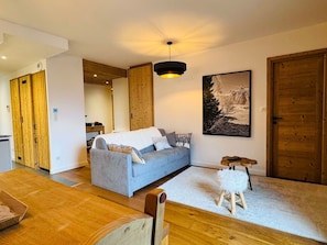 Uma sala de estar moderna com um sofá, um banquinho pequeno e um quadro na parede.