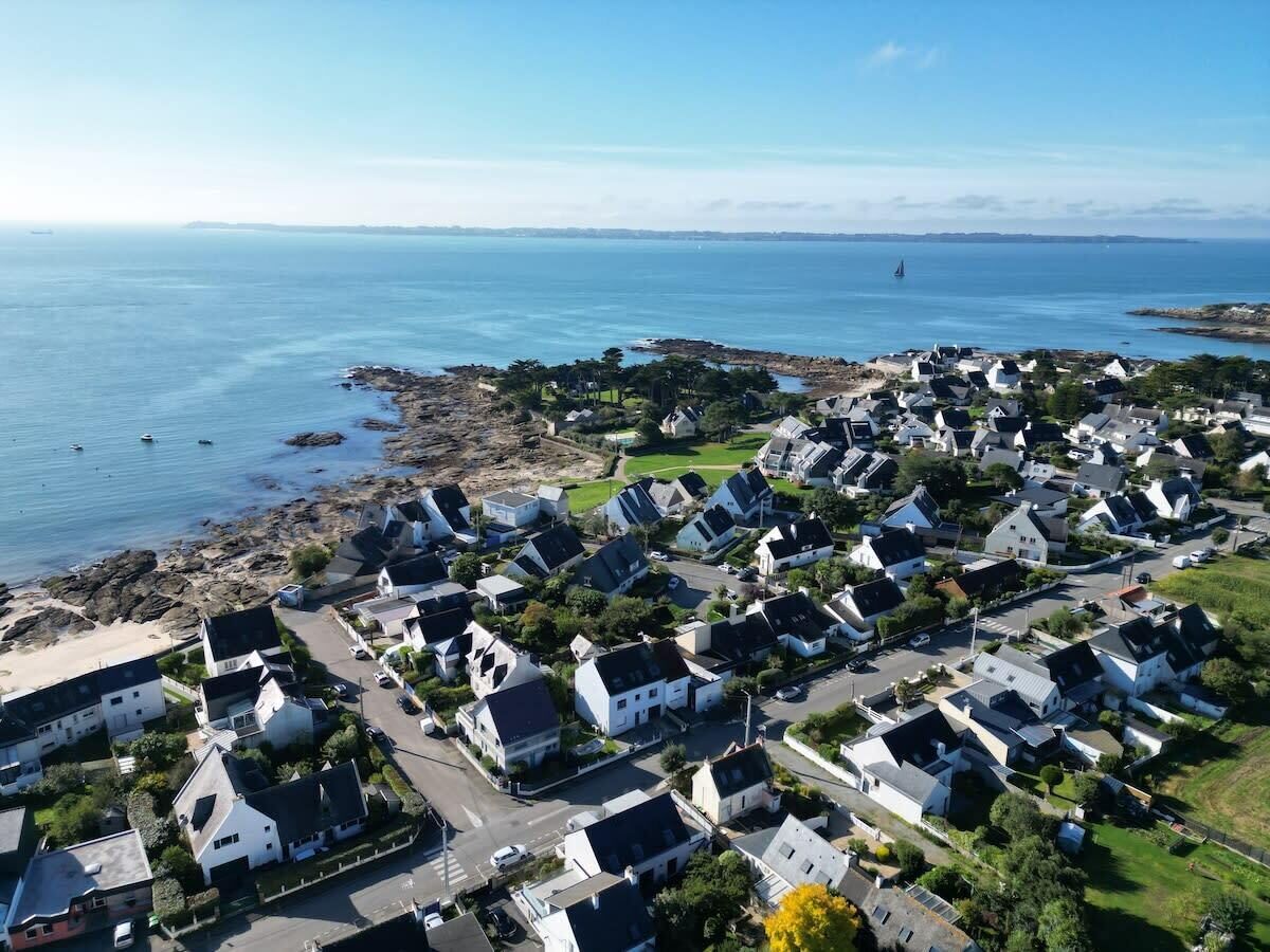 An aerial view of a coastal residential area with houses, roads, and a beach.