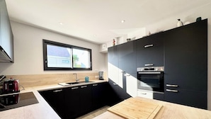 A modern kitchen with black cabinets, a wooden countertop, and a window above the sink.