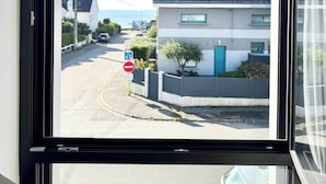 A view from a window of a building with a road outside, a no-entry sign, and a parked car.