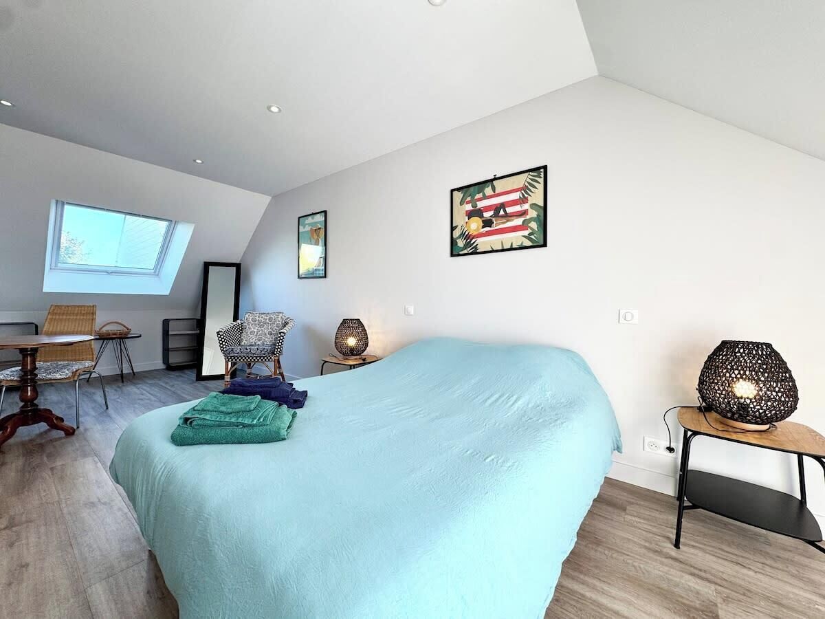 Un dormitorio moderno con una cama grande, un escritorio, una silla y una mesita de noche con lámpara.