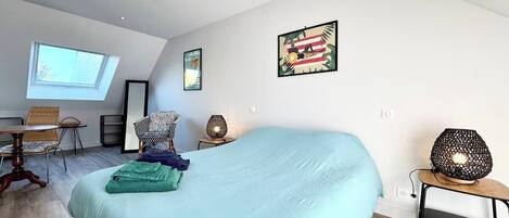 Un dormitorio moderno con una cama grande, un escritorio, una silla y una mesita de noche con lámpara.