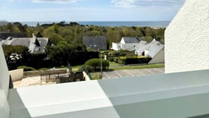 A view from a window with a skylight, overlooking a residential area with houses and a body of water. - Superbe appartement duplex - Vue mer - Piscine (Guidel)