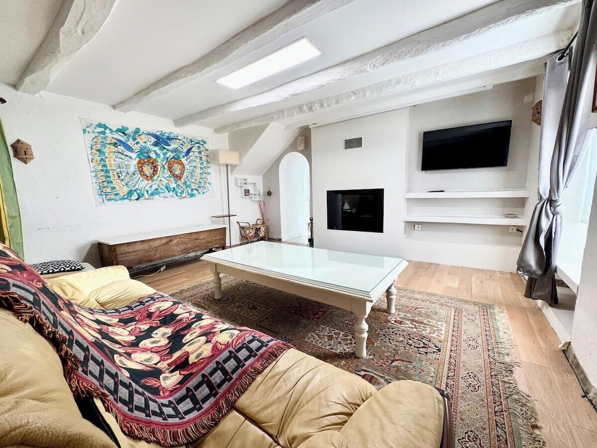 Ein gemütliches Wohnzimmer mit einer Couch, einem Couchtisch und einem an der Wand befestigten Flachbildfernseher.