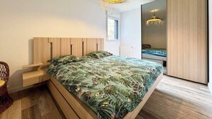 Un dormitorio moderno con una cama de madera, una mesita de noche, una silla de mimbre y un armario grande.