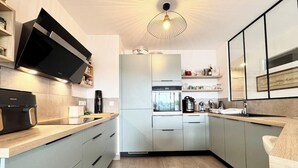 Una cocina moderna con armarios grises claros, horno integrado y una cafetera.