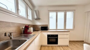 A modern kitchen with a stainless steel sink, a microwave, and an oven. - Lovely ! T2 neuf archi cosy 1 (Quimperlé)