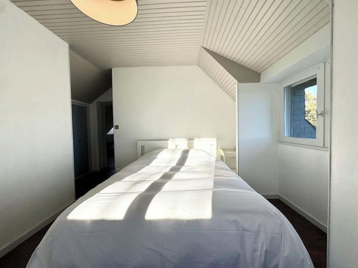 Une chambre à coucher avec un grand lit, une fenêtre et une porte donnant sur une autre pièce.