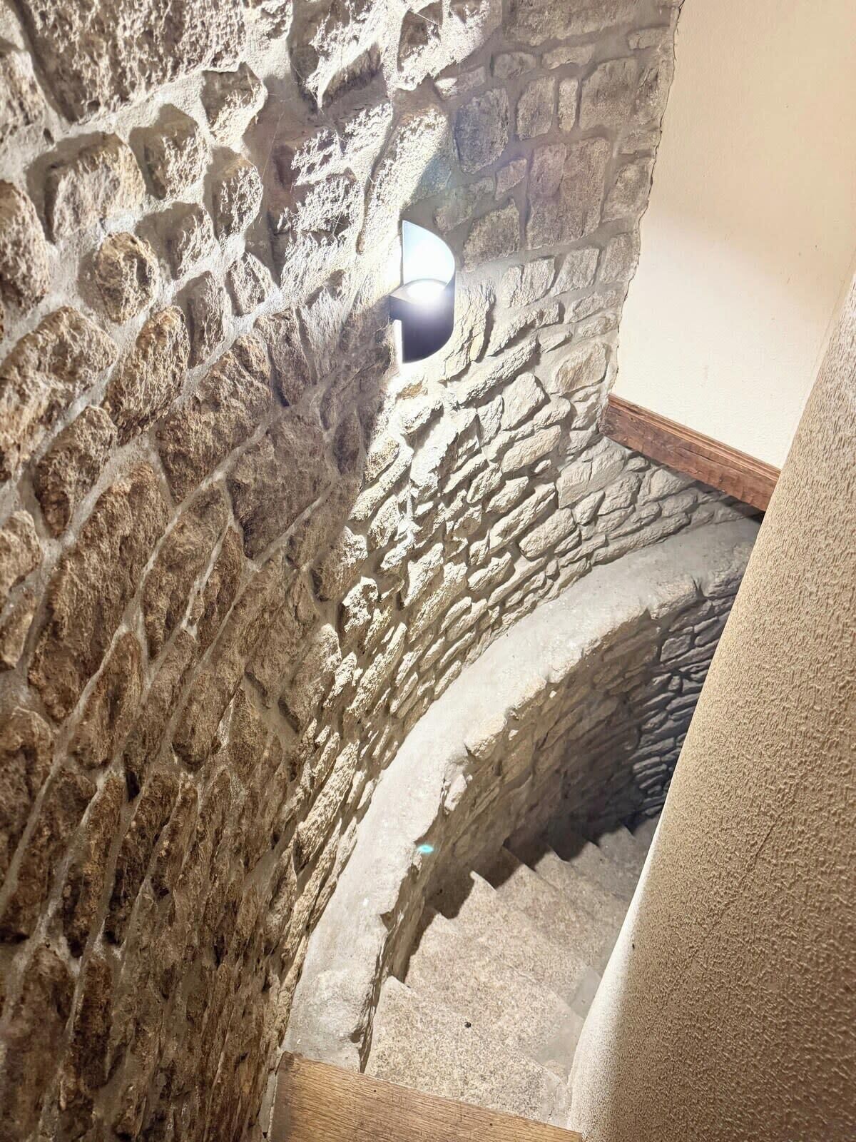 A stone staircase with a light fixture on the wall.