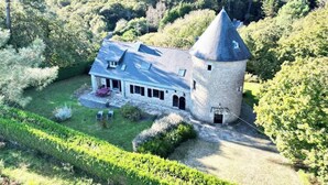 A castle-like building with a tower, surrounded by lush greenery and a well-maintained lawn.