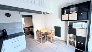 Une cuisine compacte avec une table et des chaises, une bibliothèque intégrée et une horloge au mur.