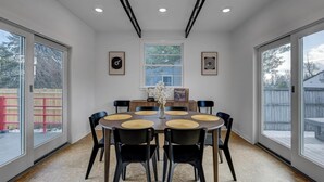 A dining room with a round table, black chairs, and a vase with flowers.