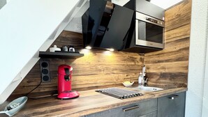Una cocina moderna con encimera de madera, una cafetera roja, un microondas y un lavabo.