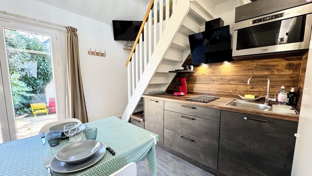 Cocina compacta con comedor, microondas integrado y una escalera que sube a un nivel superior.