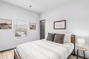 A bedroom with a bed, a bedside table with a lamp, and two framed pictures on the wall.