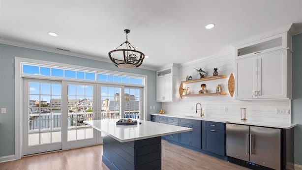 Una cocina moderna con una isla grande, muebles blancos y vistas de la ciudad a través de amplias ventanas.