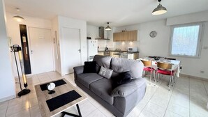 A modern living room with a grey sofa, a coffee table, and a dining area with a table and chairs.