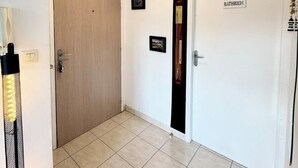 A hallway with a wooden door, a white door labeled "BATHROOM", and a wall-mounted light fixture.