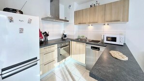 A modern kitchen with a refrigerator, microwave, stove, and wooden cabinets.