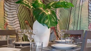 A dining table set with plates, cutlery, and glasses, with a large potted plant in the center. - Timberline Retreat – King Bed, Fireplace & Pool! (Fort Collins)
