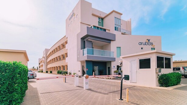 A modern hotel with a flat facade, multiple balconies, and a clear sky. - Spacious 2BR Condo w/ Free Parking near Palm Beach (Noord)